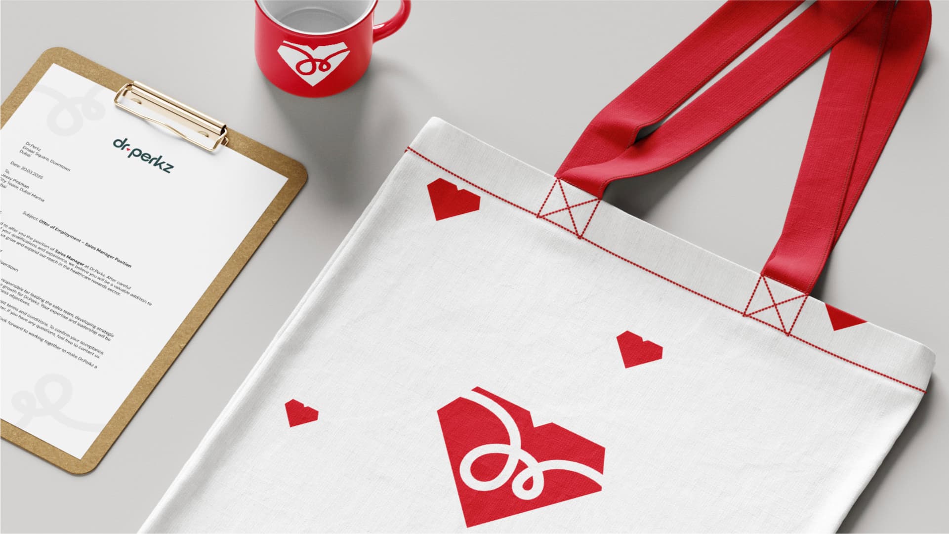 Dr.Perkz stationery mockup — letterhead on a clipboard, a red enamel mug and a white tote bag printed with the heart symbol