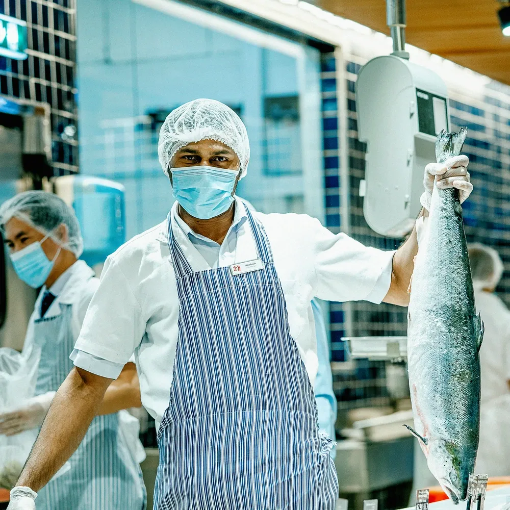 LuLu social post — fishmonger holding up a fresh catch at the seafood counter