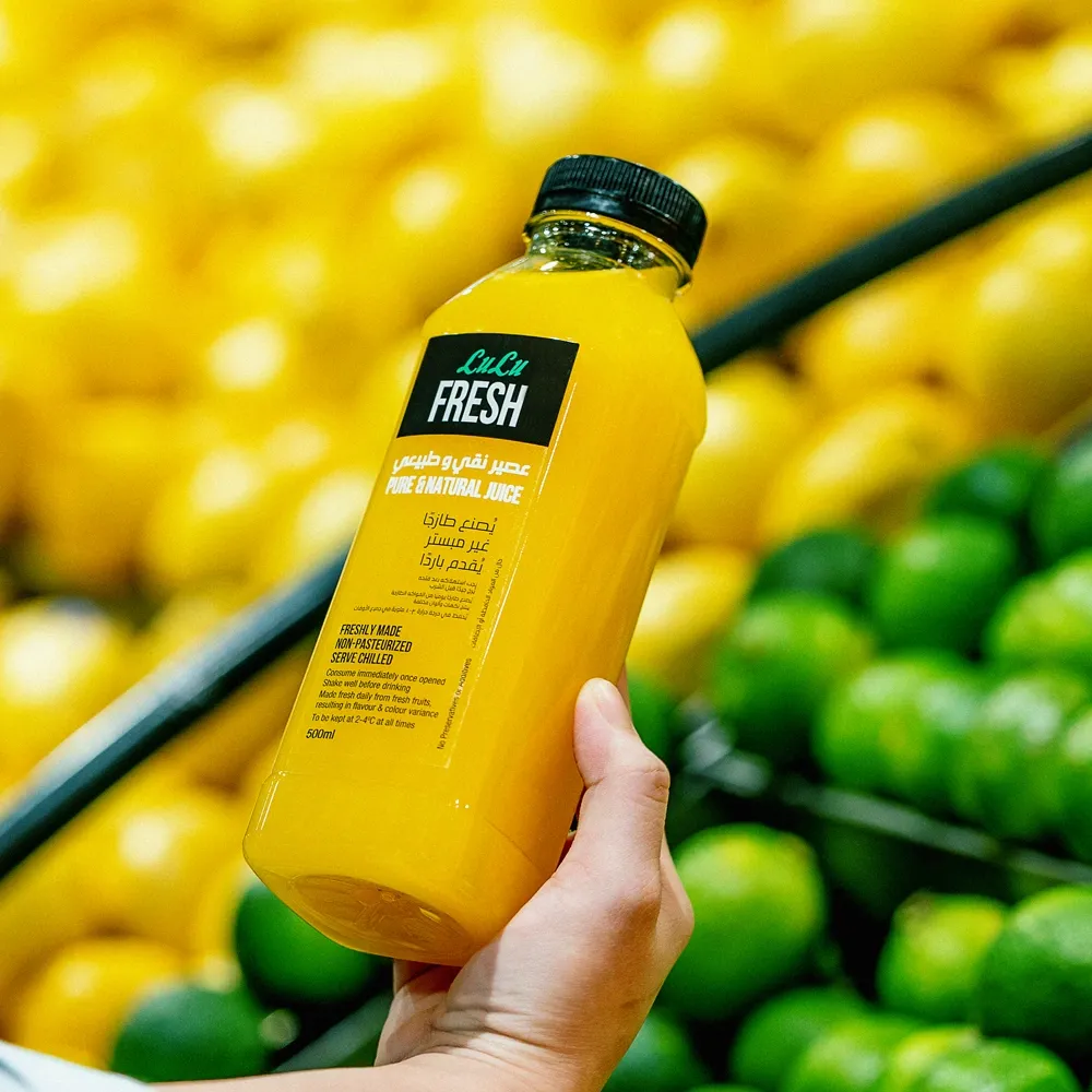 LuLu social post — hand holding a bottle of fresh juice in the produce aisle