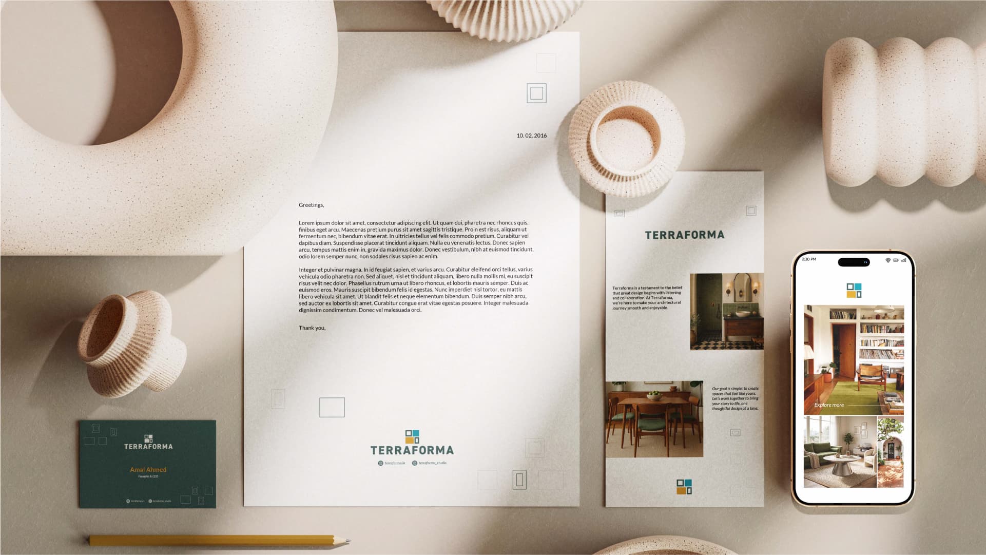 Stationery flat lay with Terraforma letterhead, business card, brochure and a mobile site view on a warm neutral surface